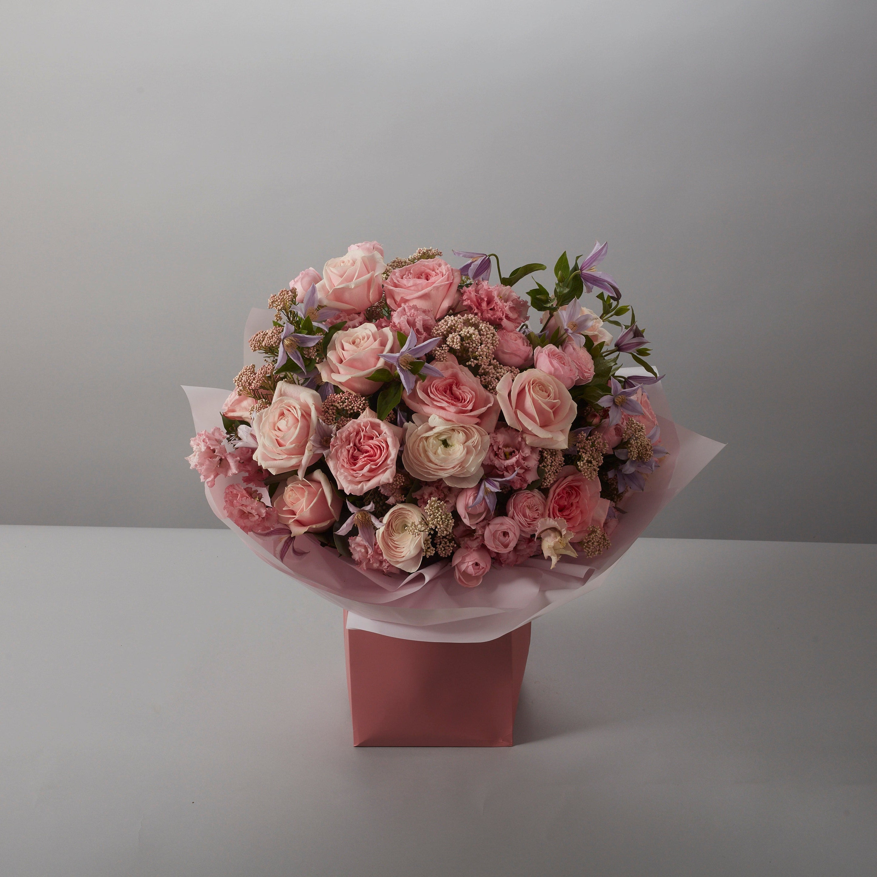 Bouquet of pink flowers in a pink box on a gray background