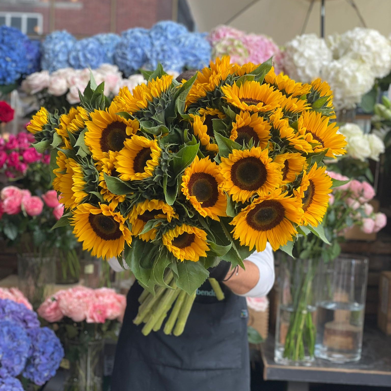 Person holding a bouquet of sunflowers at Petals at Bibendum